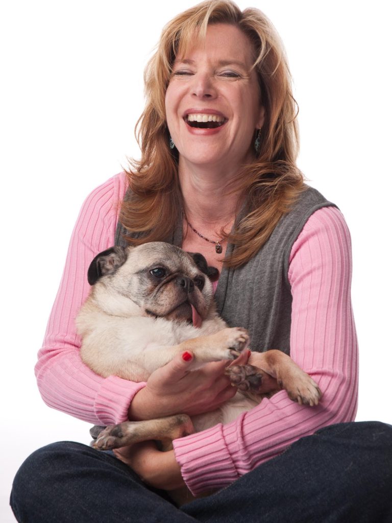 Woman with her pug in her lap, laughing.